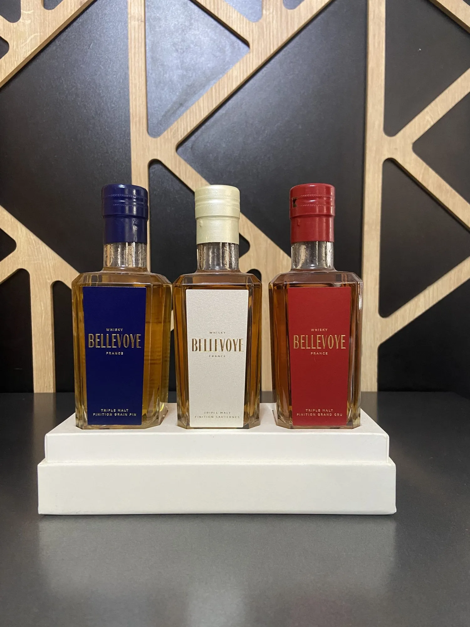 Coffret découverte de trois whiskies Bellevoye — bleu, blanc et rouge — sur le comptoir de la cave.